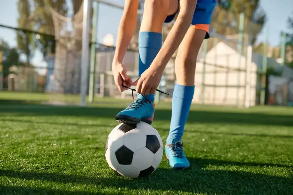 Boy tying shoe on a soccer ball 2026 03 16 04 29 04 utc groot