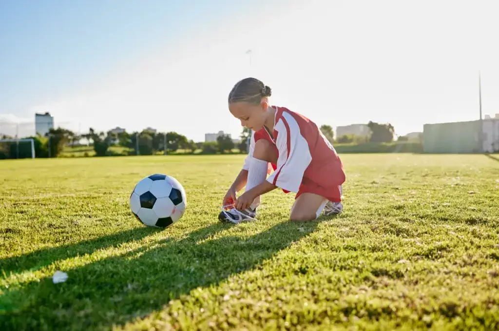 Girl tying shoelaces on green soccer field 2026 03 25 02 20 06 utc groot